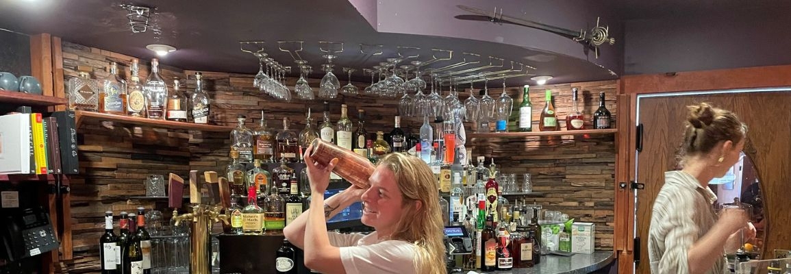 This image of a hotel bar and bartender mixing a drink depicts a career site that relates to hospitality majors.